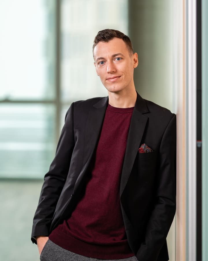 Adrian Ley steht lächelnd an einer Glaswand in seinem Büro in Wien